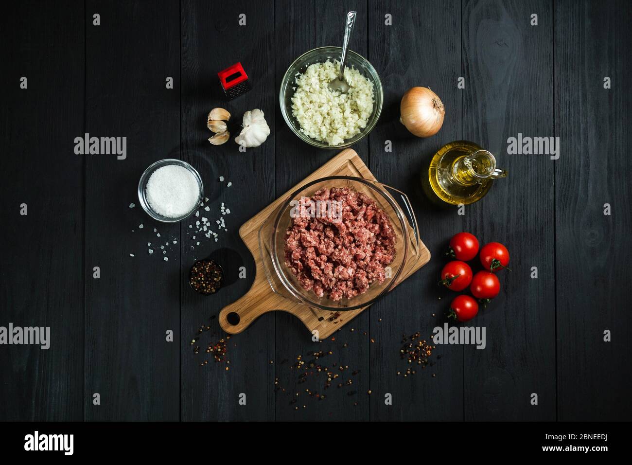 Raw minced meat with ingredients on black wooden boards. View from above. Stock Photo