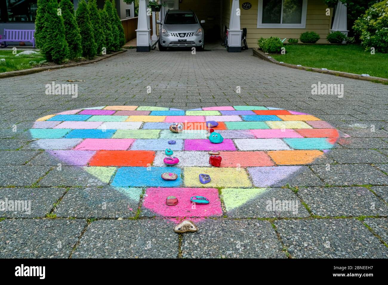Chalk heart drawing and rocks with messages on driveway during Covid-19 pandemic, Vancouver, British Columbia, Canada Stock Photo