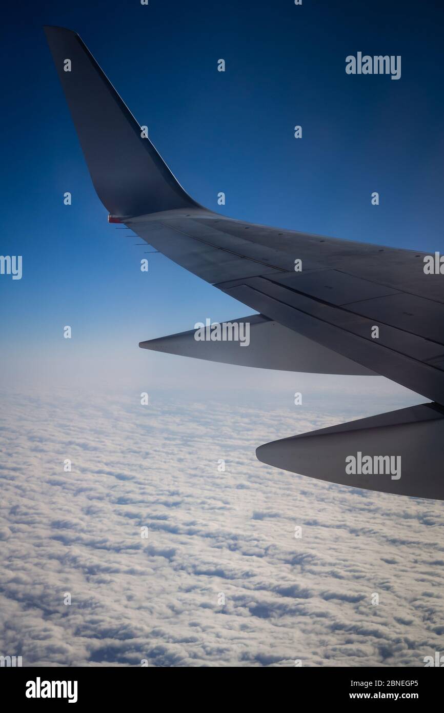 Airplane wing above the clouds on a blue sky Stock Photo - Alamy