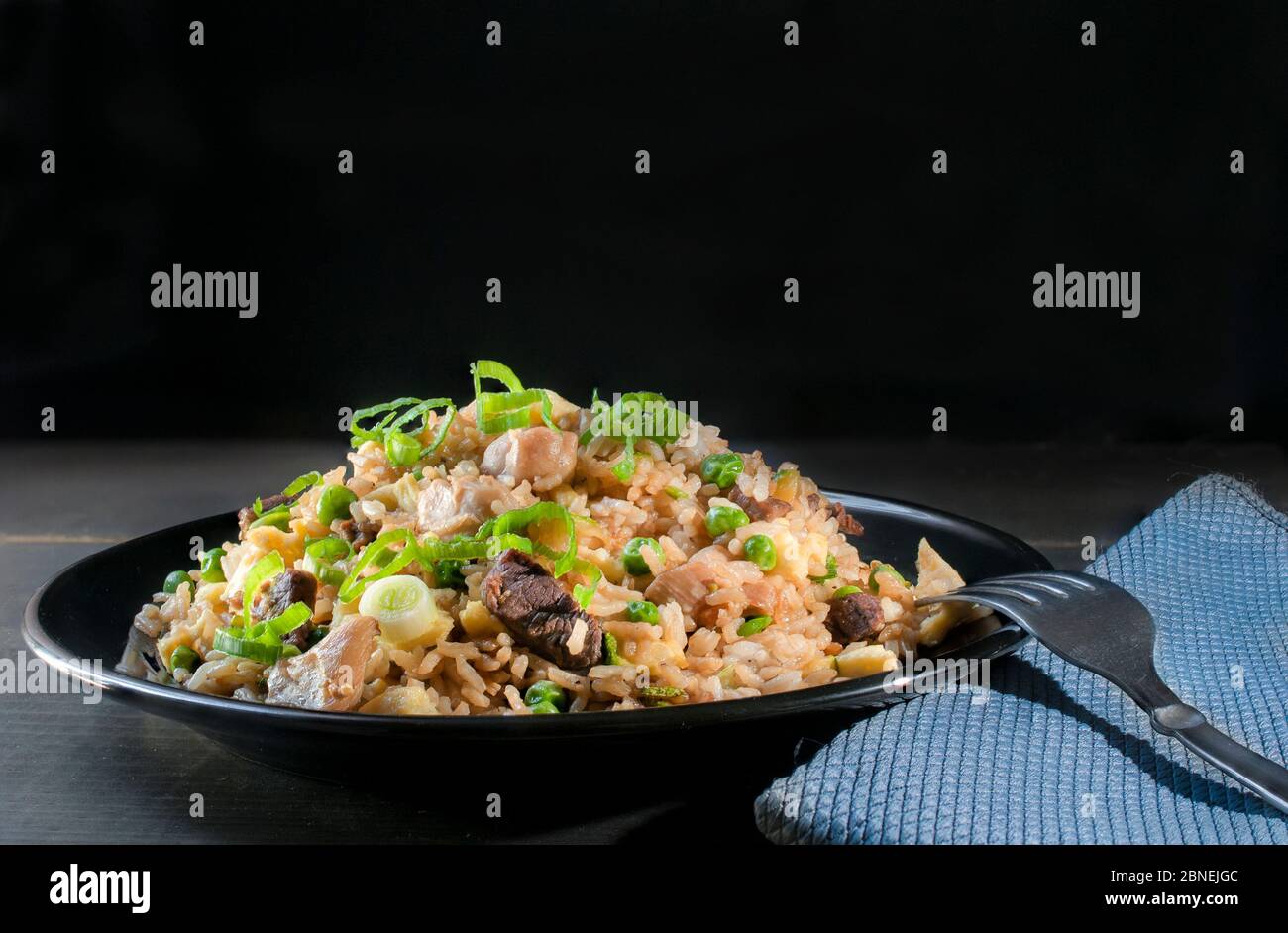 Chinese Cantonese fried rice with chicken, peas, and chives on top, in