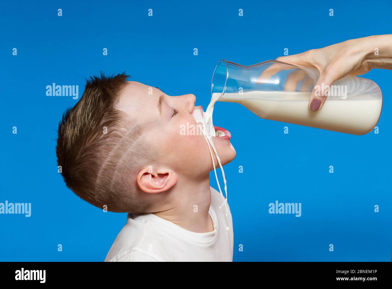 Happy Boy drinking Milk from bottle Isolated on Blue Background. Milk got by the boys mouth