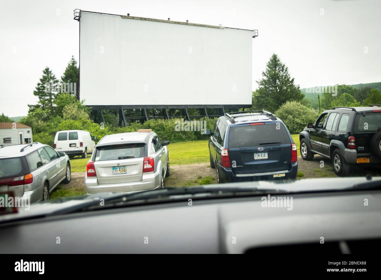 The Mahoning Drive-In Theater movie screen stands in the distance; the cars of movie goers in the foreground Stock Photo