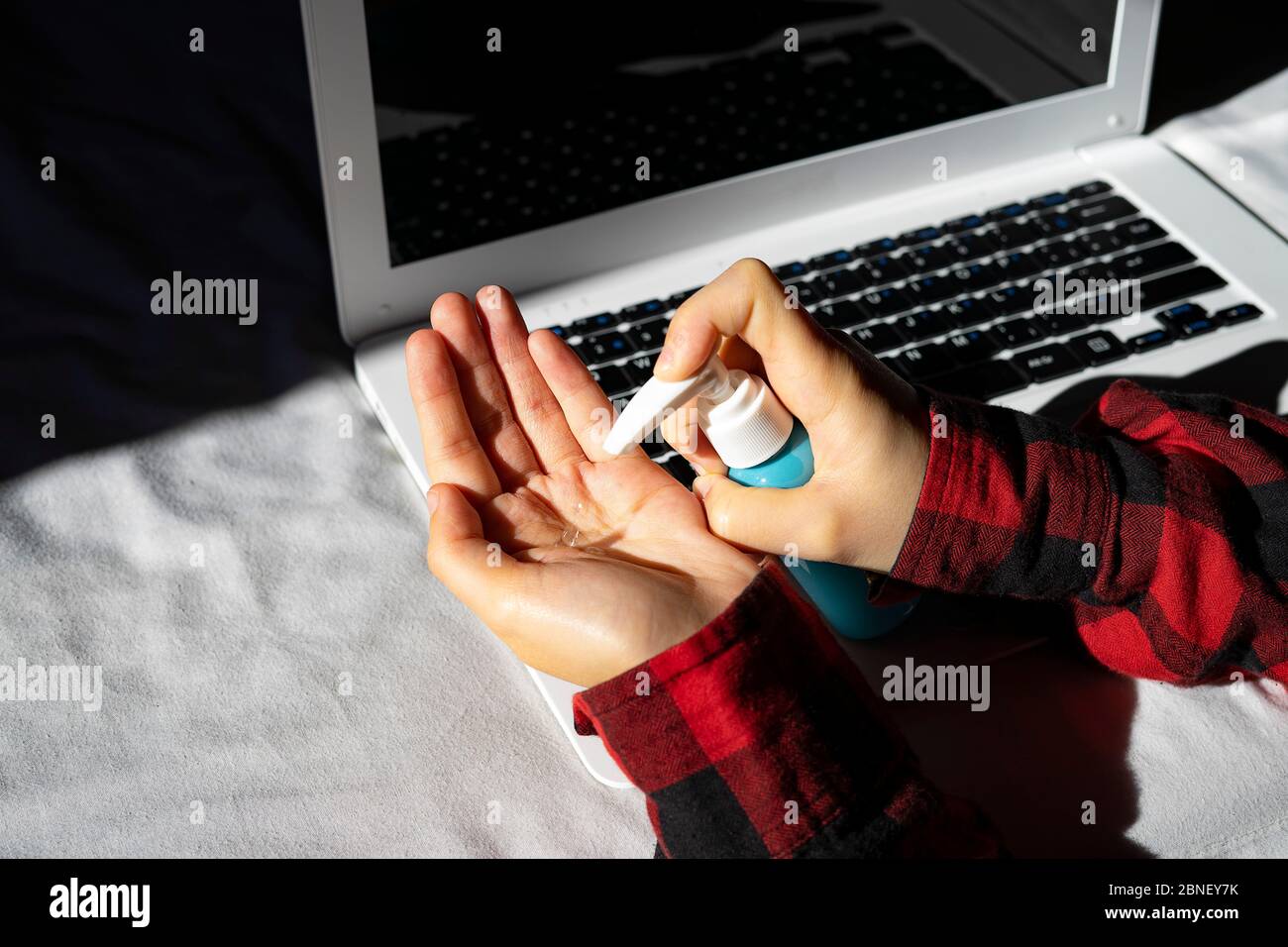 office worker disinfecting his hands at his workplace. Protection against COVID-19. Stock Photo