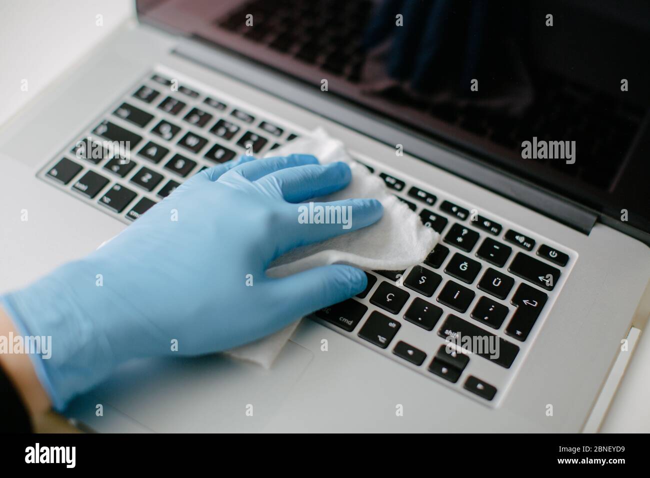 The woman cleans the keyboard of her computer to protect it from coron Stock Photo