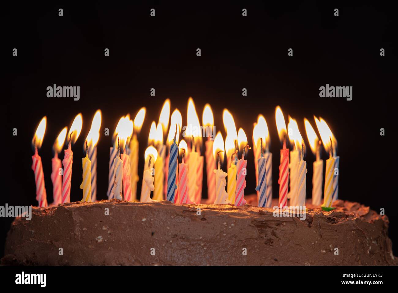 Closeup shot of a birthday cake with lighted colourful candles on a black  background Stock Photo - Alamy
