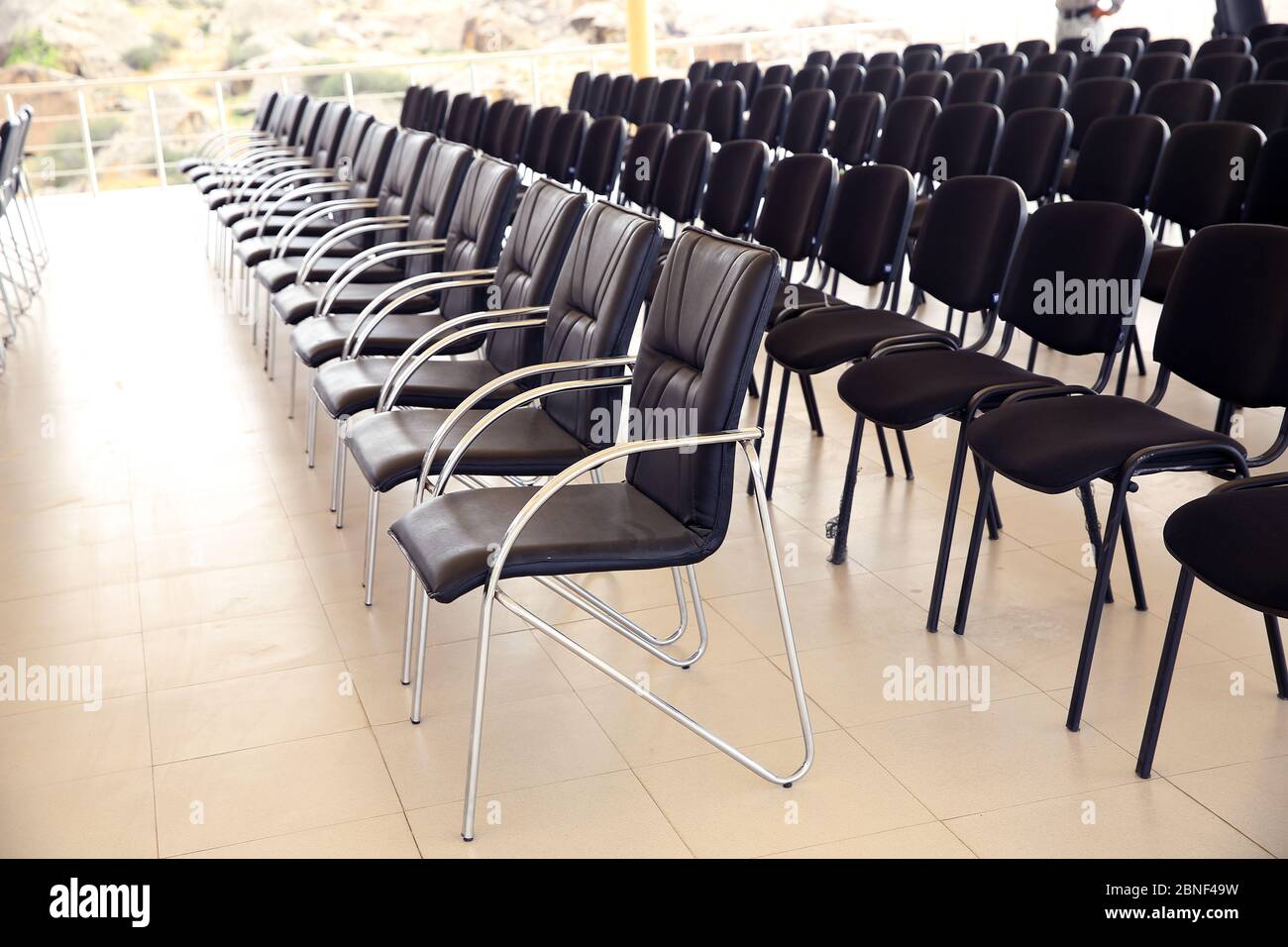 Uniqueness concept. Rows of black folding chairs empty in a conference room . Unique throne or