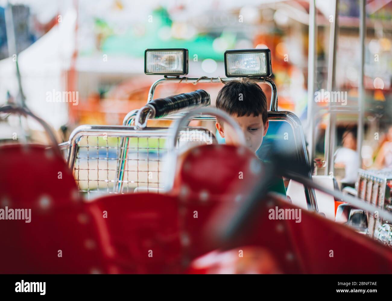Beautiful boy enjoying in funfair and riding on colorful carousel car ...