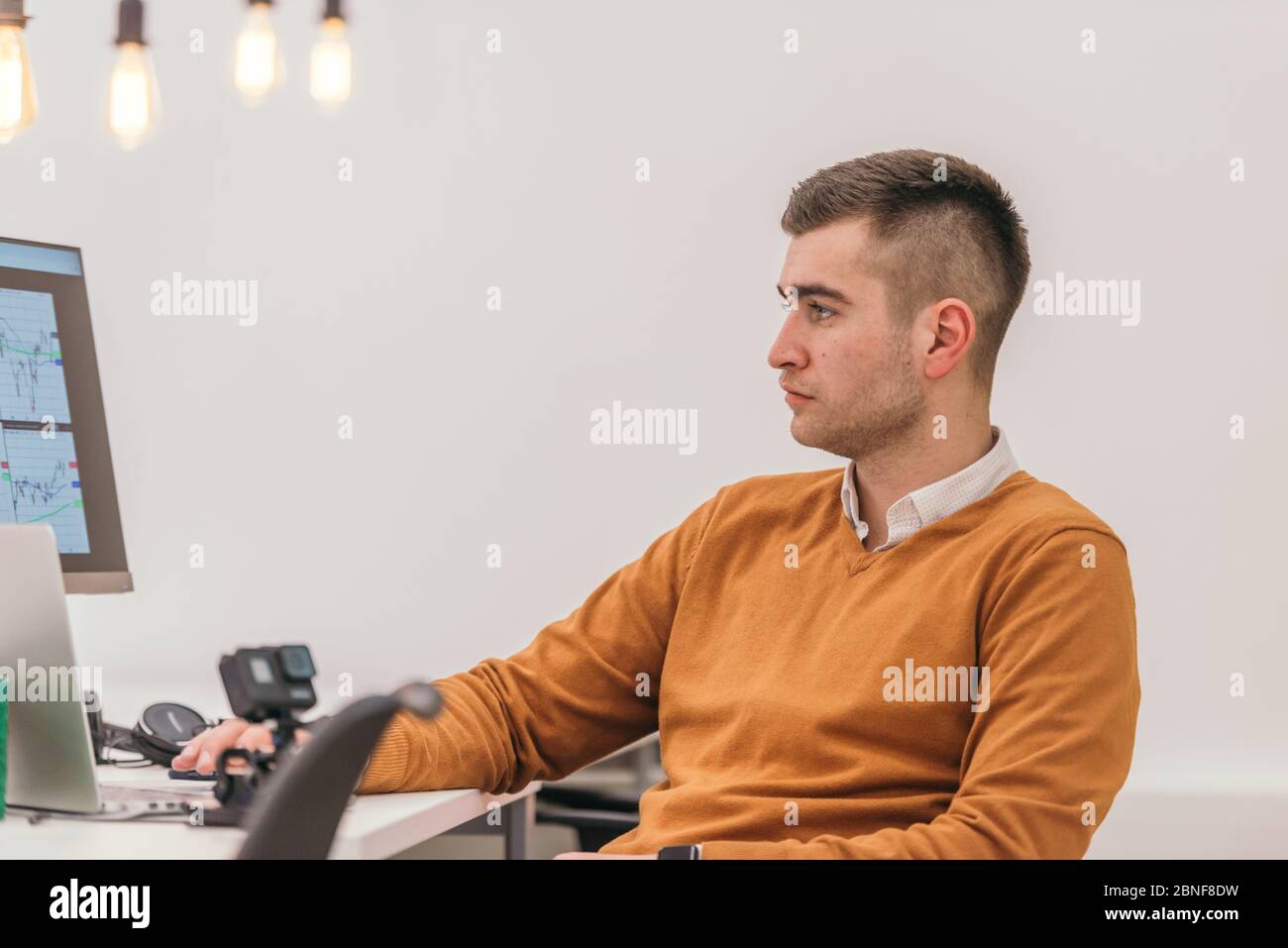 A casually dressed employee performing daily activities while working on a pc. Stock Photo