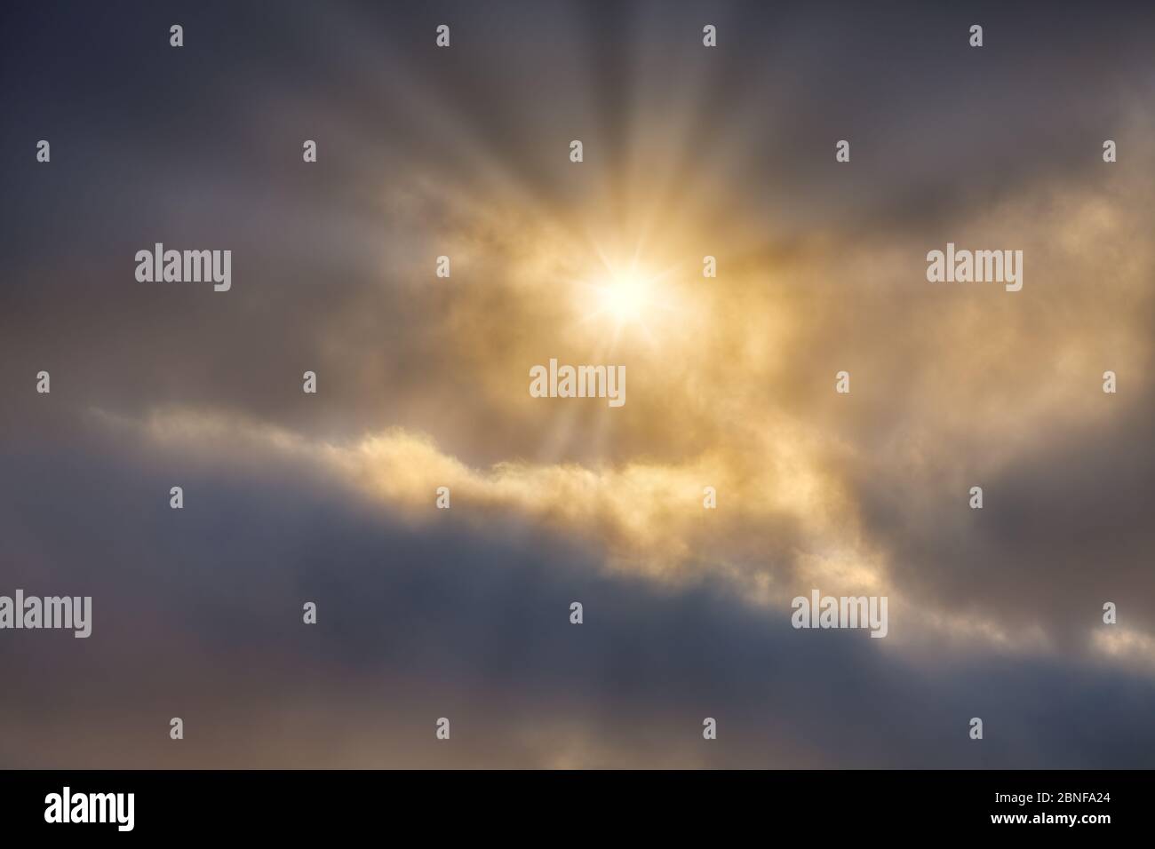 A Sunburst of Light Breaks Through the Glowing Bright Detailed Clouds Stock Photo