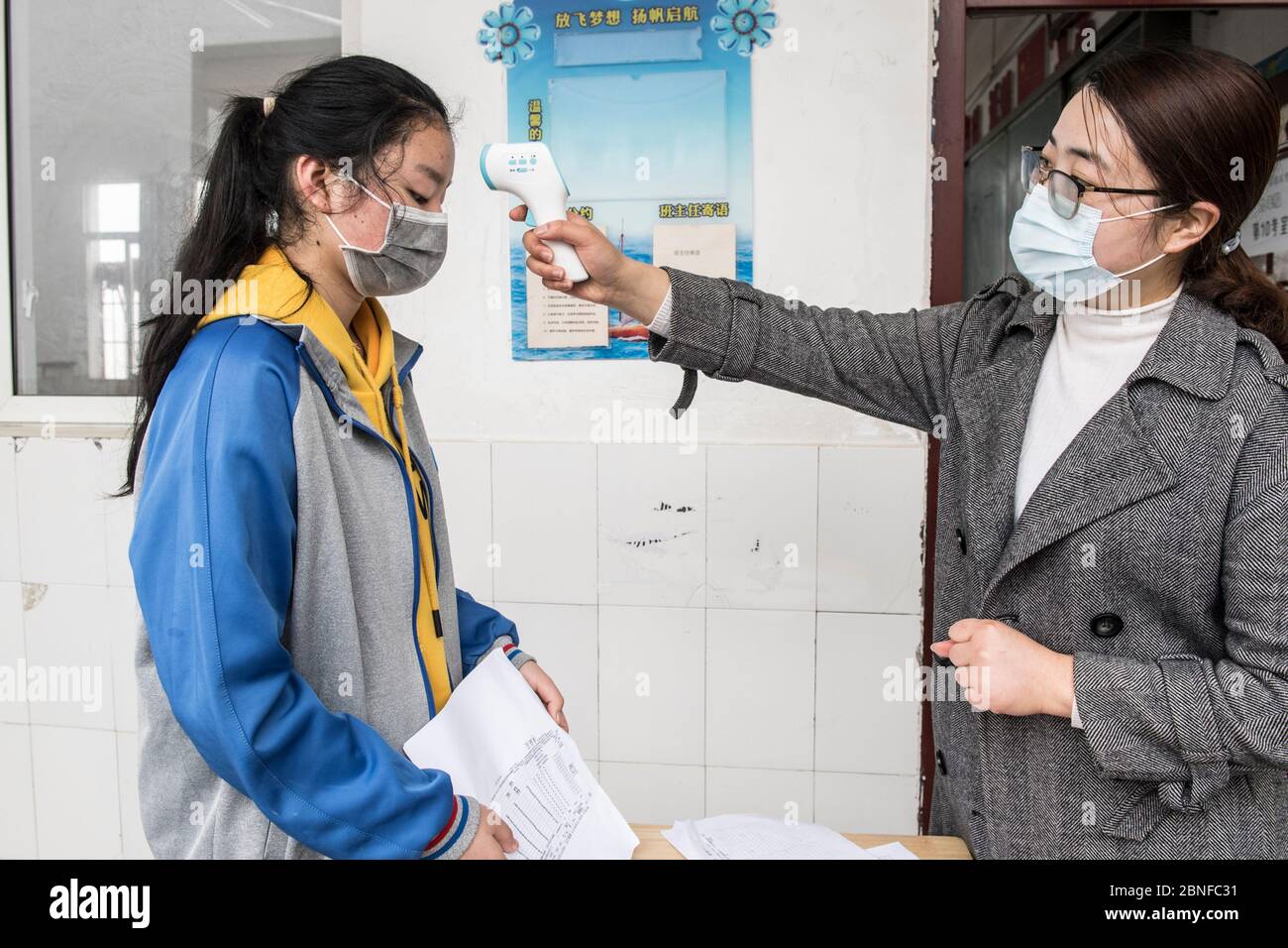 Students with face mask on queue to take a temperature before entering the classroom after a two-and-half winter vacation at a local middle school, Xi Stock Photo