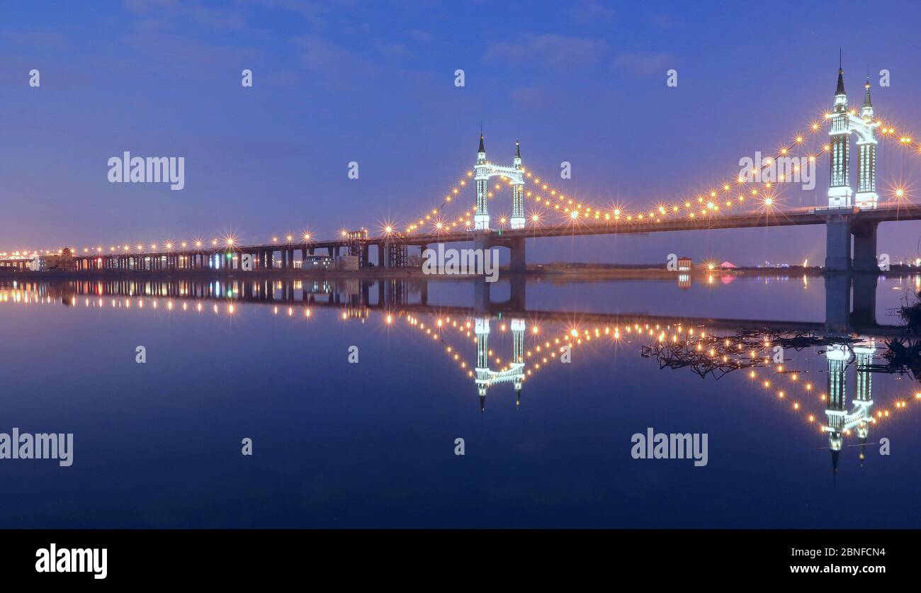 When night comes and skyscrapers and Yangmingtan Bridge along the Songhua River light up, reflections of these local landmarks bring citizens to a won Stock Photo