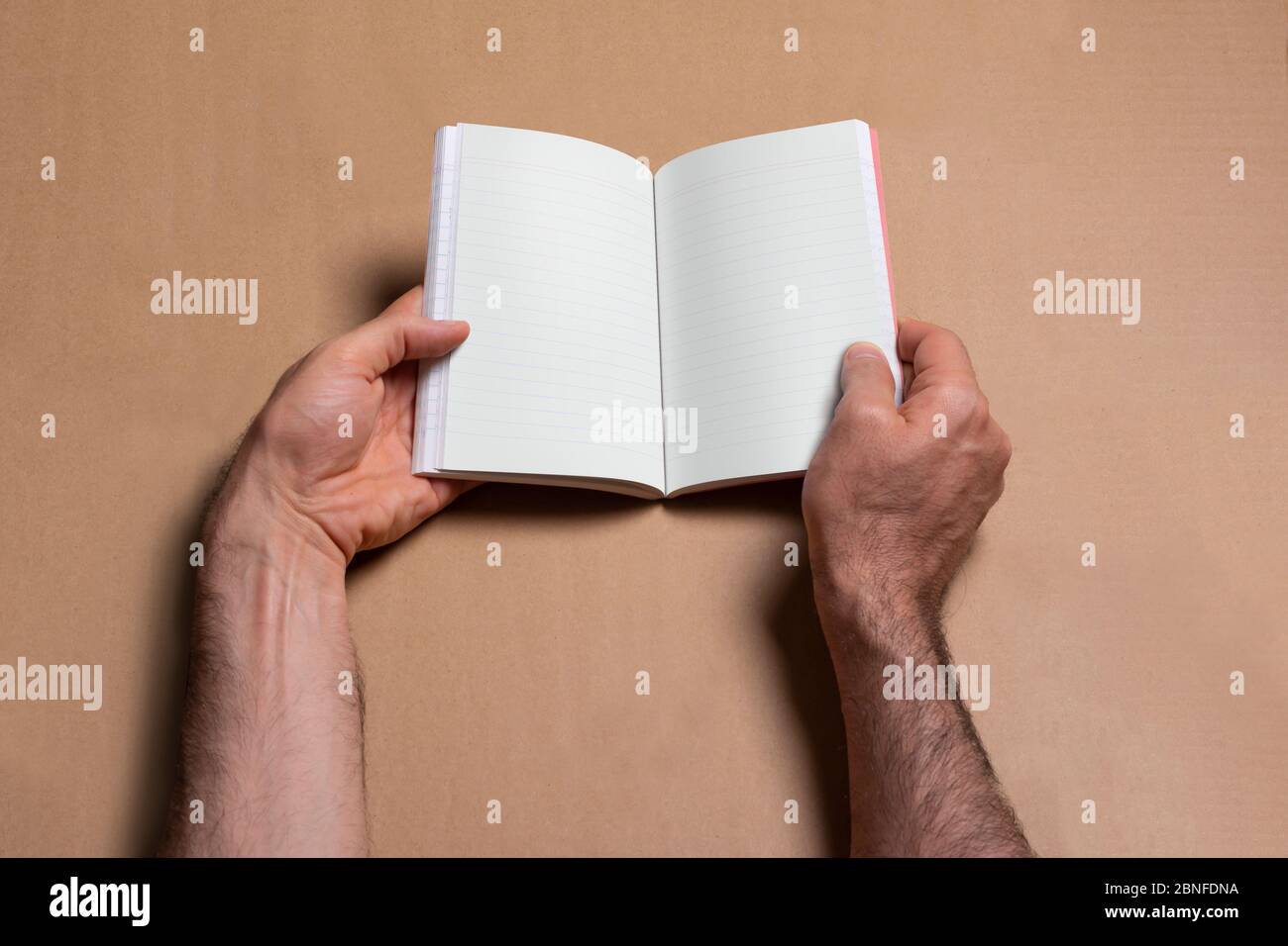 Male hands holding an opened note bookcatalog with blank pages on