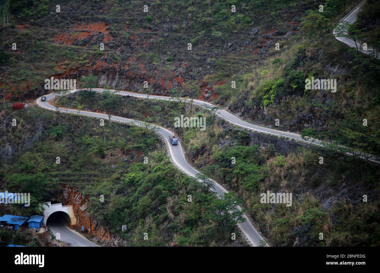 An aerial view of vehicles moving on a zigzag road, which connects mountain villages with cities