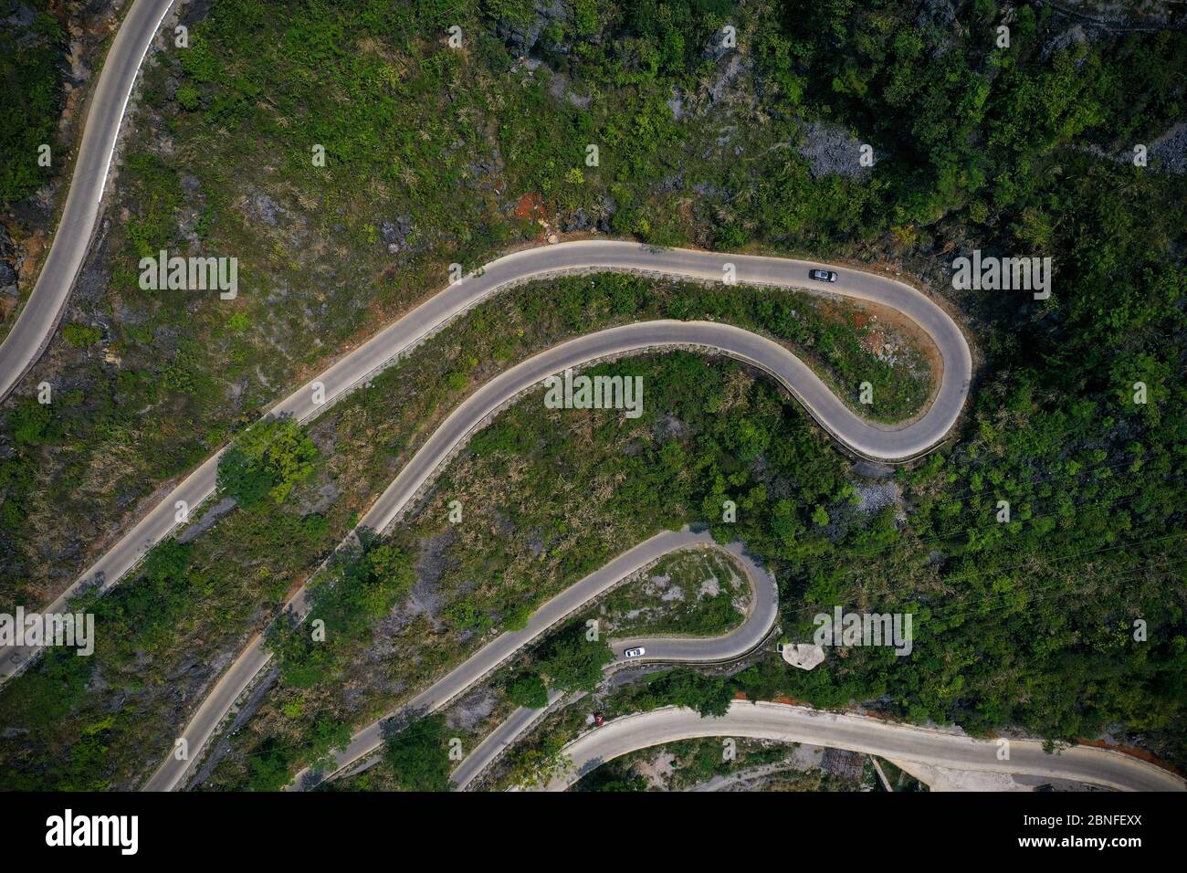 An aerial view of vehicles moving on a zigzag road, which connects mountain villages with cities
