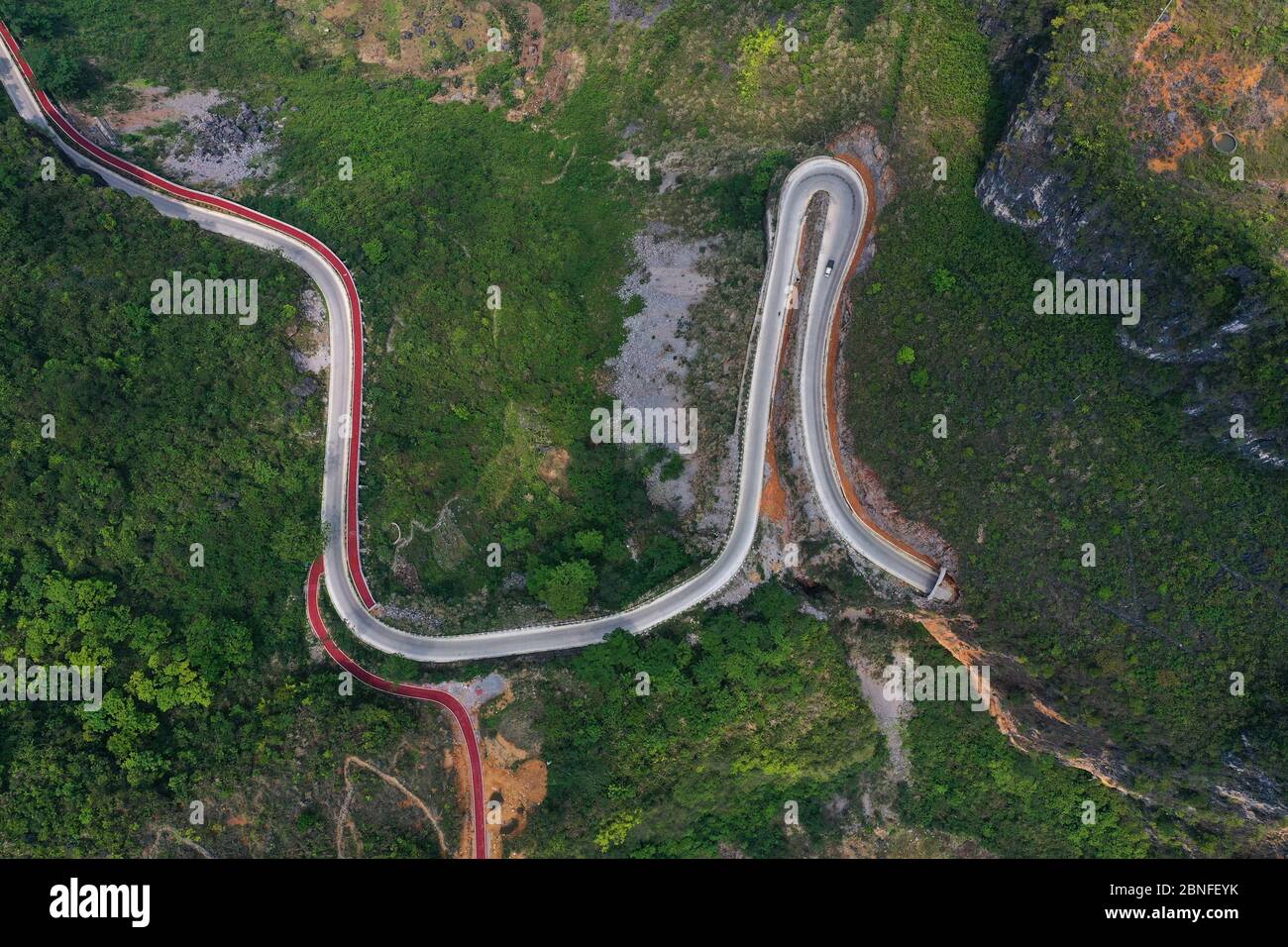 An aerial view of vehicles moving on a zigzag road, which connects mountain villages with cities