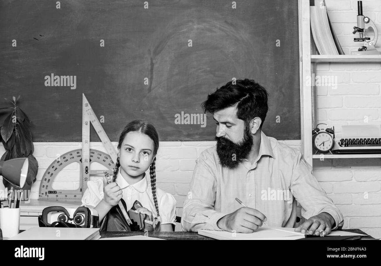 Analyzing strategy. daughter study with father. Teachers day. back to school. Private teaching. private lesson. knowledge day. Home schooling. small girl child with bearded teacher man in classroom. Stock Photo