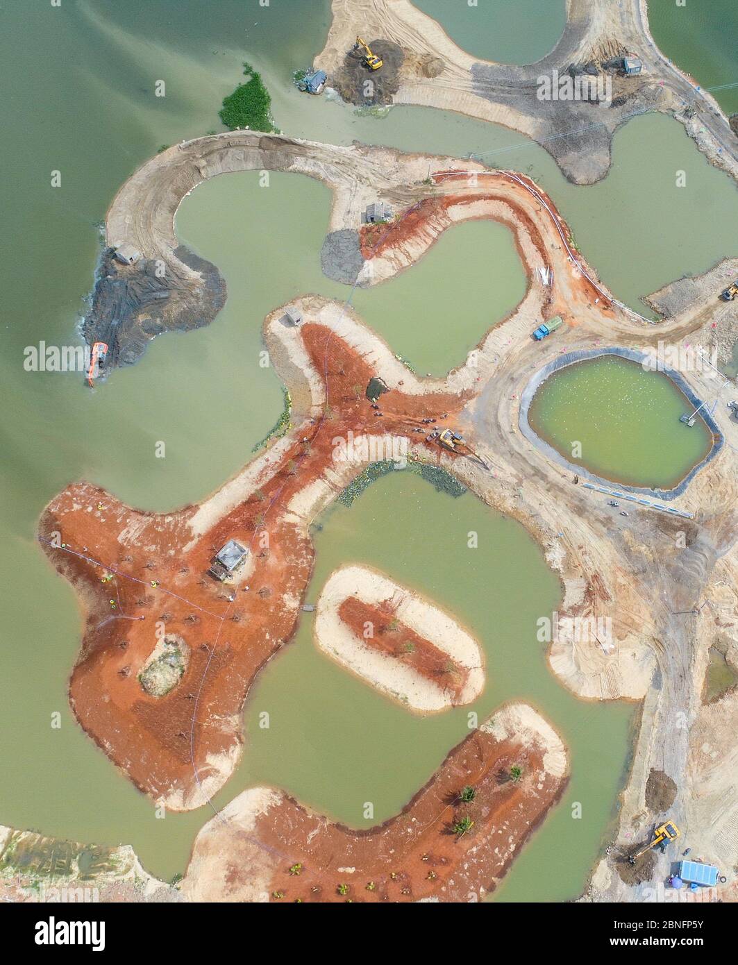 Aerial view of trucks and diggers working to rehabilitate the land in Miayahe River aera in Haikou city, south China's Hainan province, 22 April 2020. Stock Photo