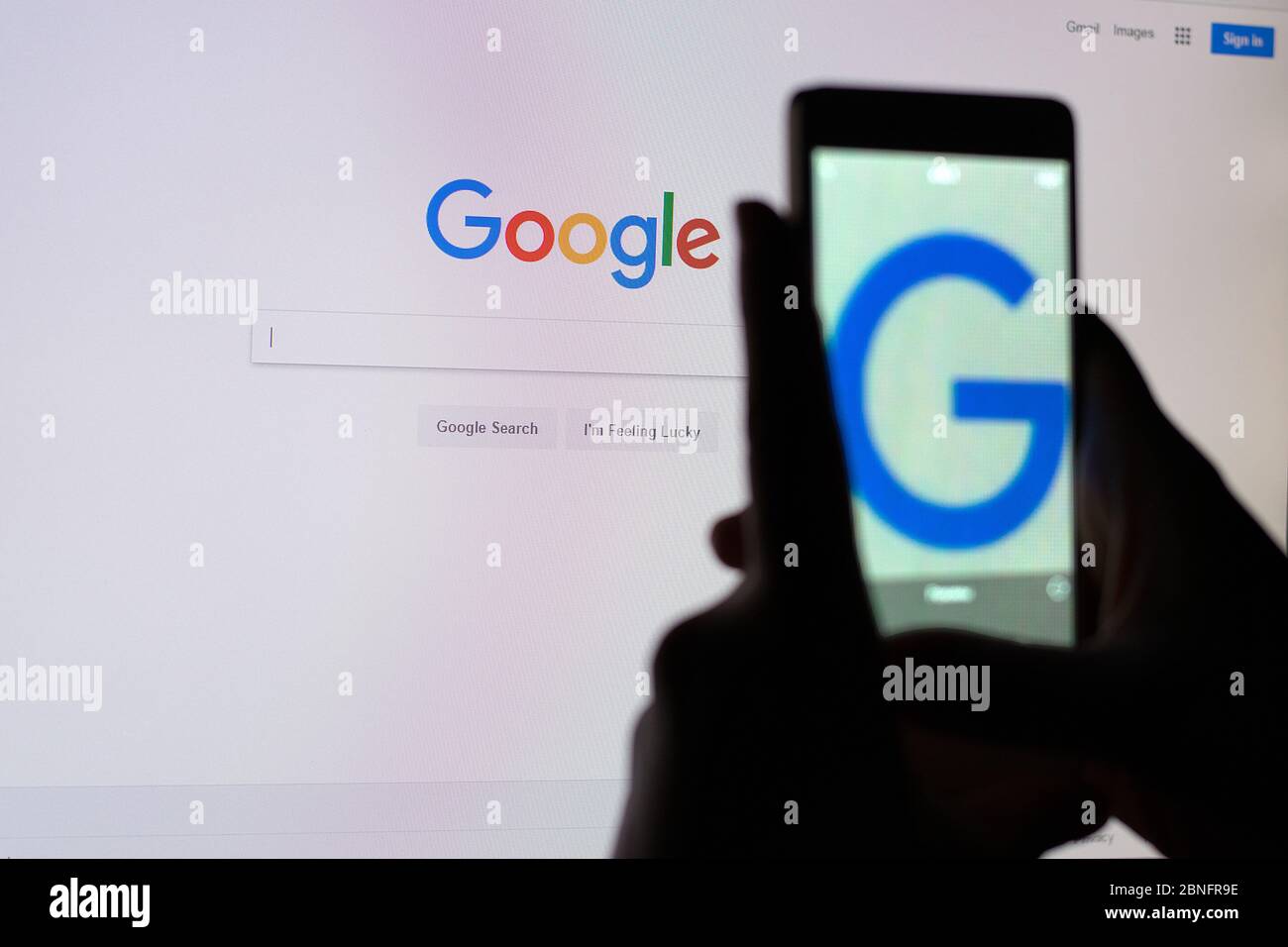 A person takes a picture of the monitor screen with a Google search string. Stock Photo