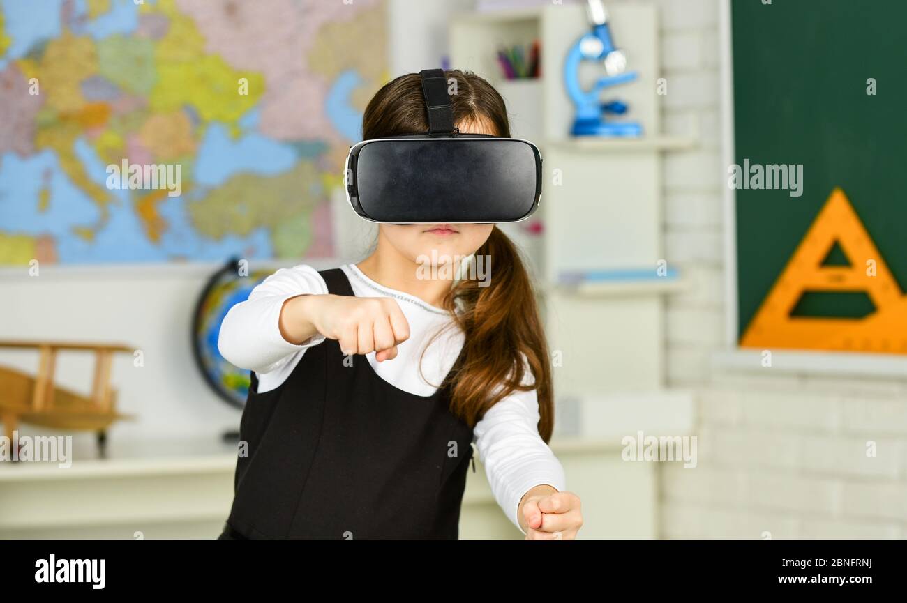 Virtual classes. Driving lessons. Science Class. VR technology. schoolgirl using virtual reality helmet. Virtual reality headset. Teenager student girl in classroom. Play game. Go around obstacles. Stock Photo