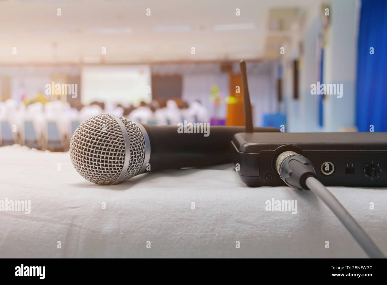 Close up old microphone wireless with box signal on the white table in business conference interior seminar meeting room and Background blur. Vintage Stock Photo