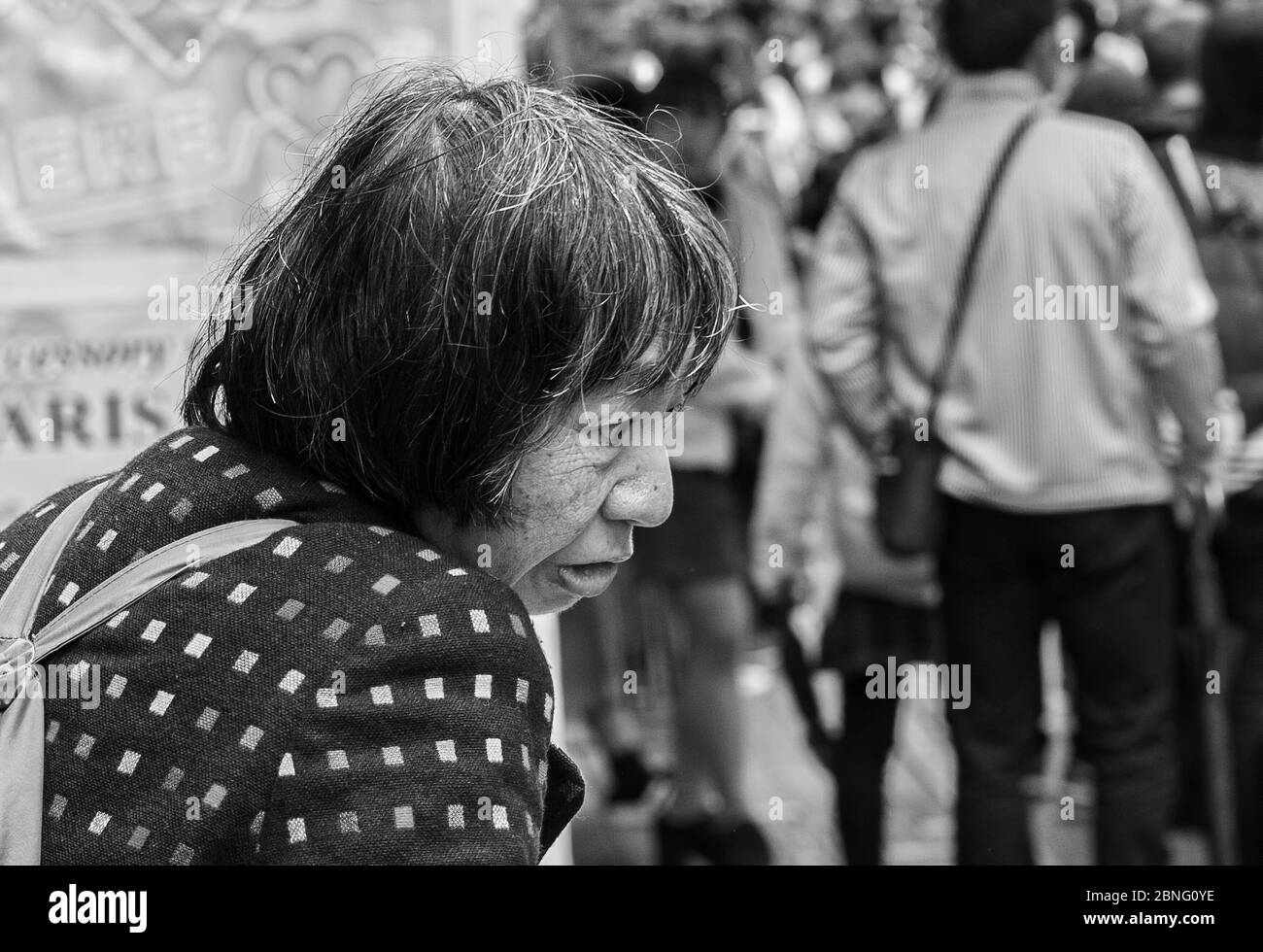 An older mentally handicapped Japanese woman sitting in front of a shop at Takeshita street in Harajuku district in Tokyo, Japan Stock Photo