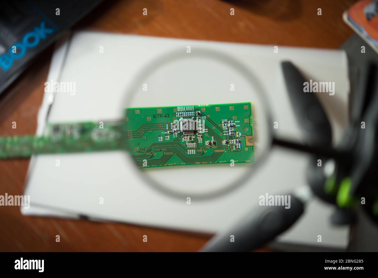 Engineer looking at a circuit board through a magnifying glass Stock ...