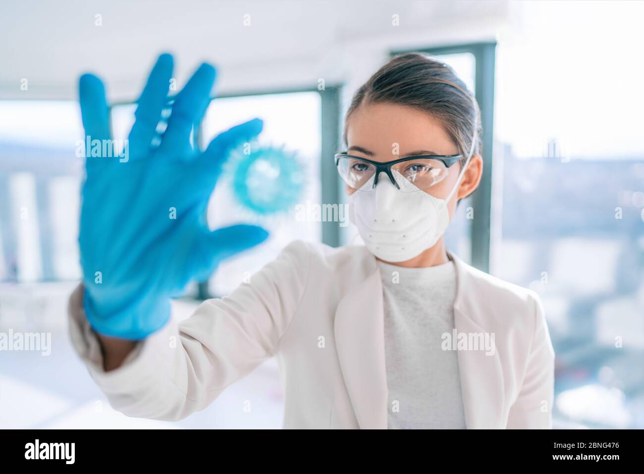 Coronavirus lab research woman researcher finding vaccine cure holding corona virus blue model of COVID-19. Stock Photo