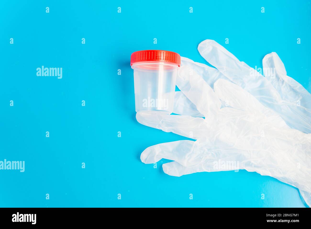 Flat lay of the medical latex gloves and empty plastic test container with copy space Stock Photo