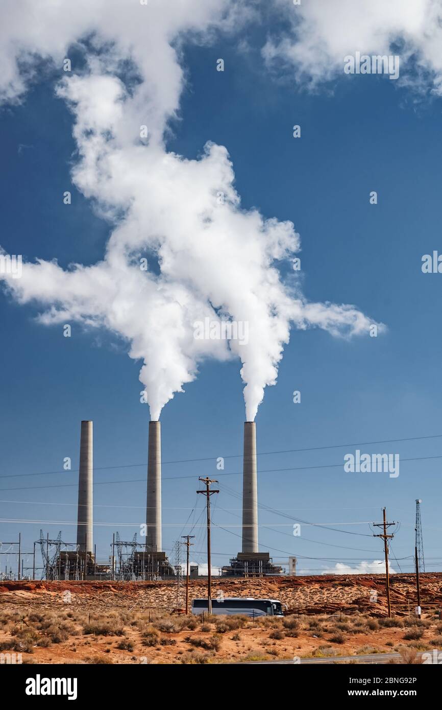 Vertical shot of steam coming out of a factory captured under the clear blue sky Stock Photo
