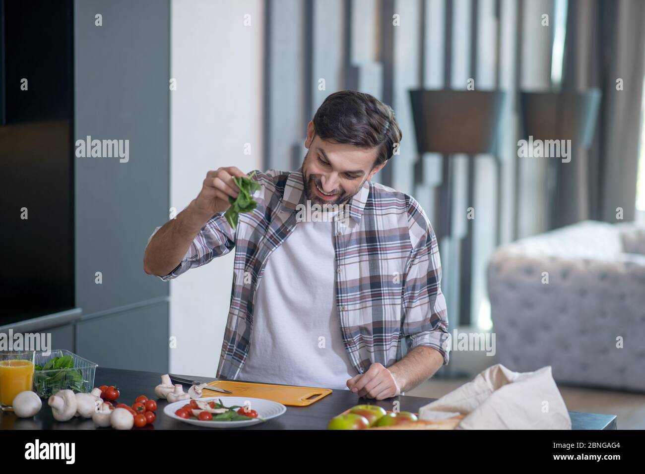 Man holding hand with arugula leaves over a plate with vegetables Stock Photo