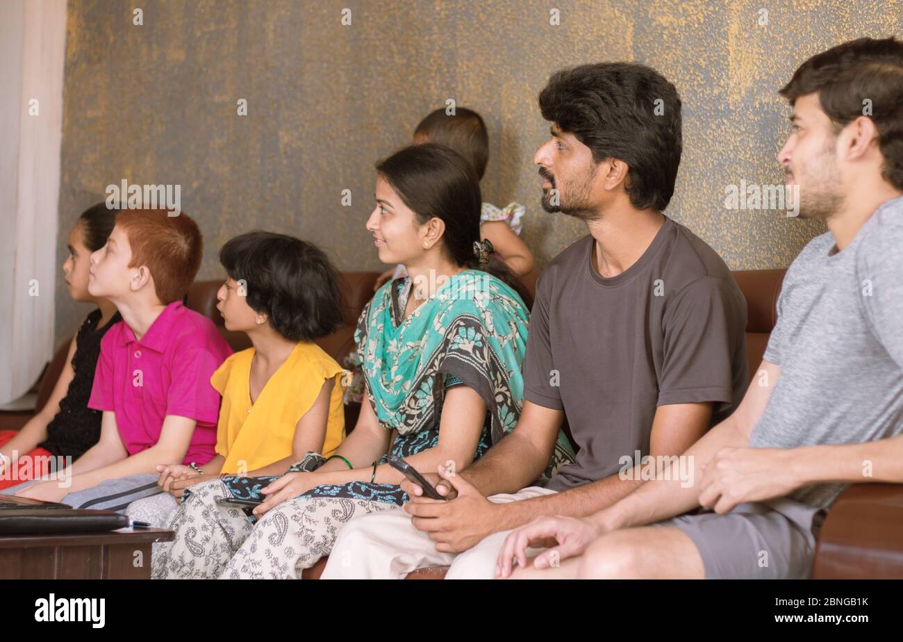 Group of family Siblings watching tv on sofa at home - concept of family bonding, togetherness, weekend entertainment and socializing Stock Photo