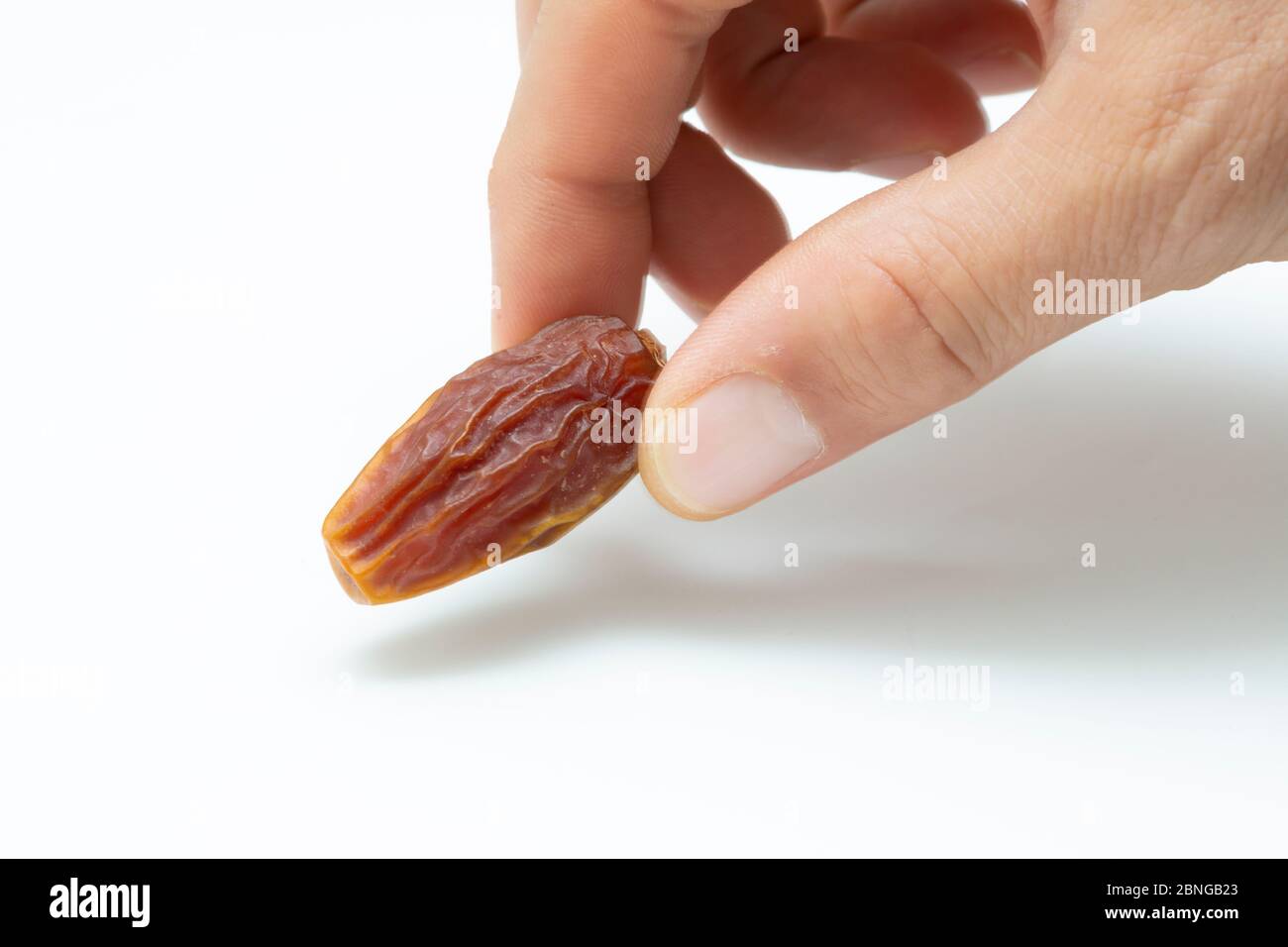 Hand holding pitted dates isolated on white background Stock Photo