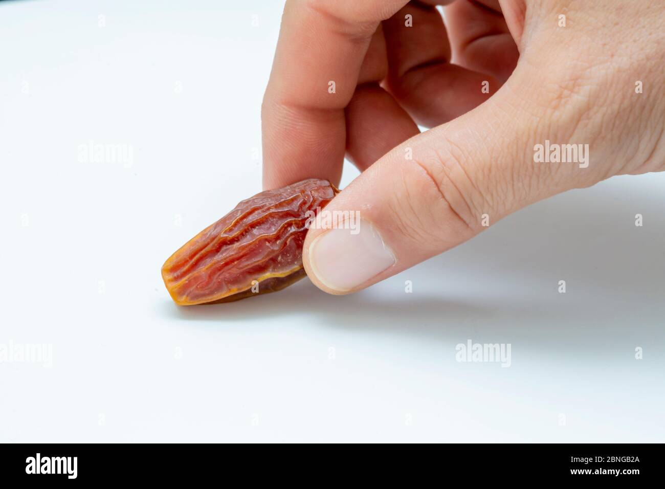 Hand holding  pitted dates isolated on white background Stock Photo