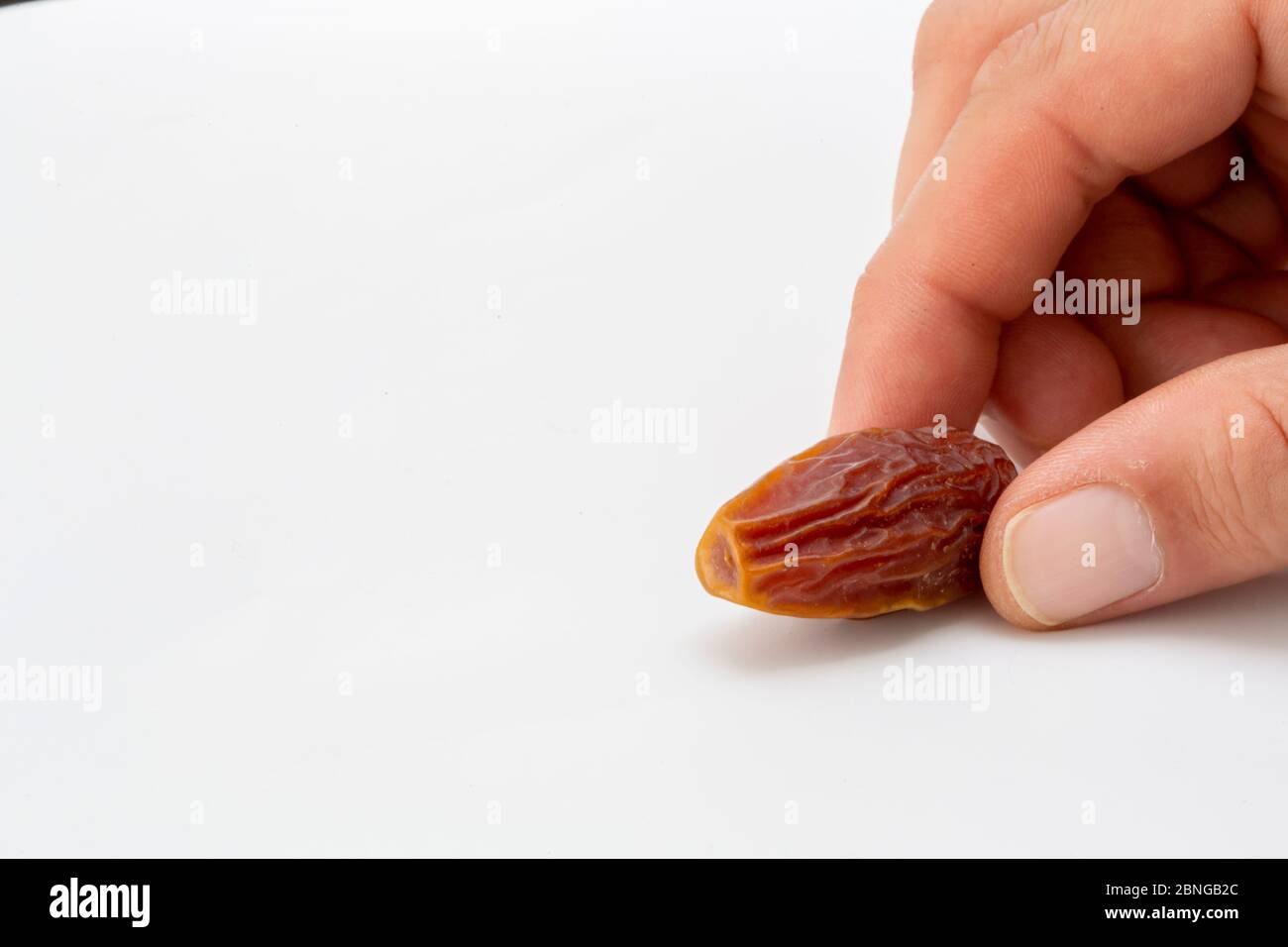Hand holding  pitted dates isolated on white background Stock Photo