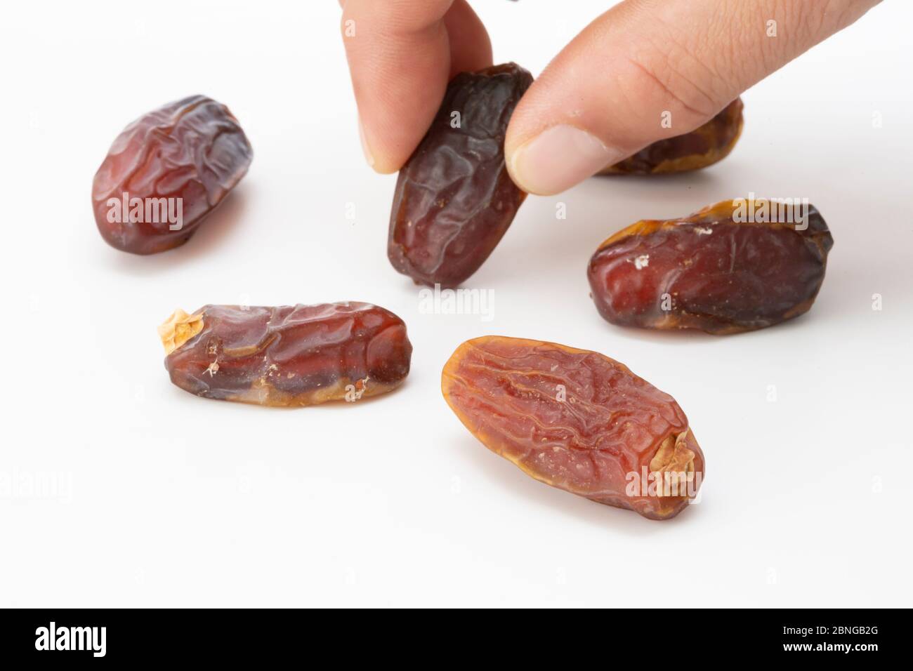 Hand holding  pitted dates isolated on white background Stock Photo