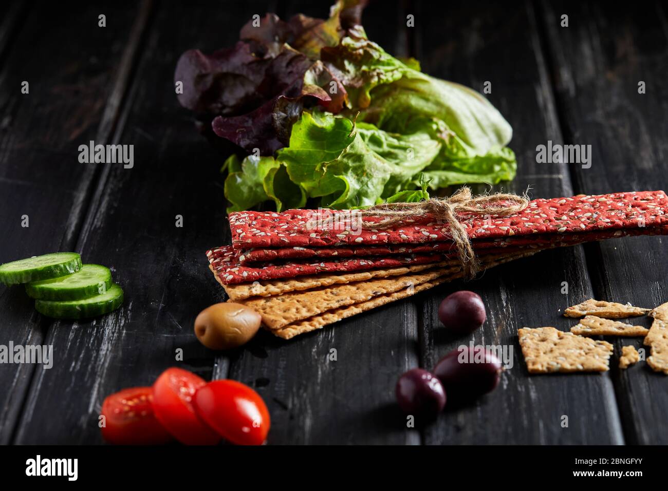 Beetroot and rye flour crackers with vegetables for making snacks on a black background. Vegetarianism and healthy eating Stock Photo