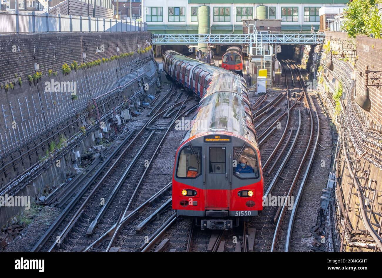 Morden Station, London, UK. 15 May 2020. On day 53 of Coronavirus lockdown a Northern Line underground train leaves Morden terminus station via the City during a quiet morning rush hour at the southern end of the Northern Line, with the driver electing to wear a face mask. Credit: Malcolm Park/Alamy Live News. Stock Photo