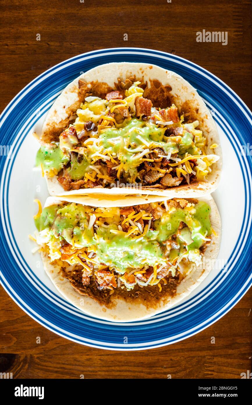 Top view of ground meat soft tacos with cheese with salsa verde on a plate on a wooden table Stock Photo