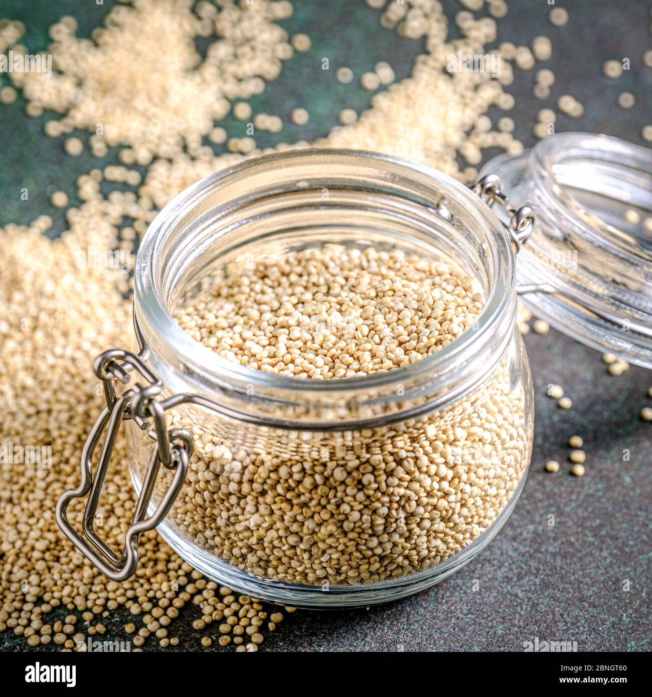 White raw quinoa in glass jar on green rustic background. Stock Photo