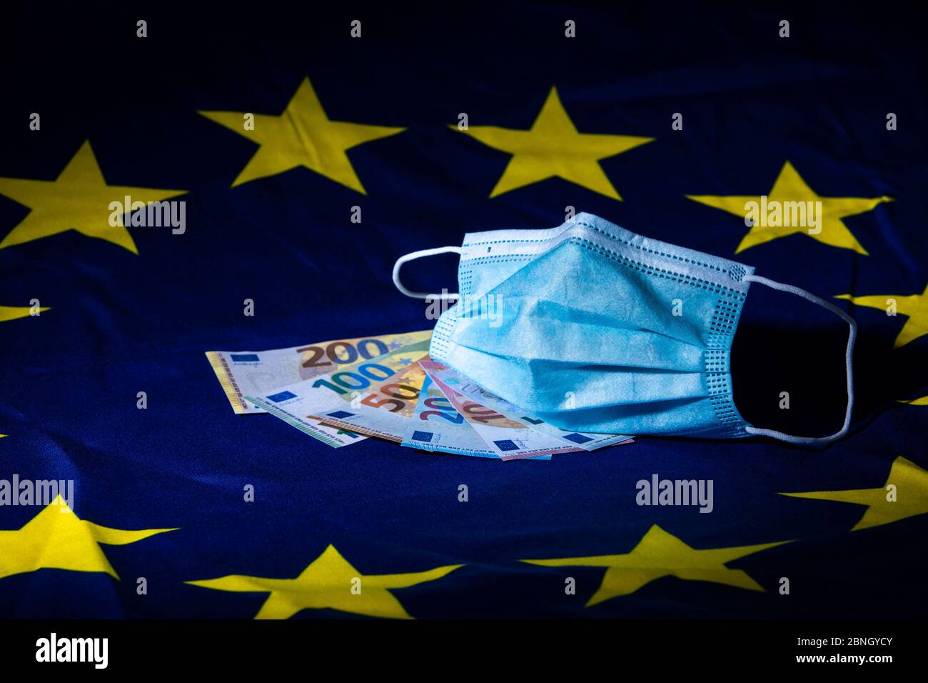 wrinkled face mask and money on a European flag illustrating a concept of health business Stock Photo