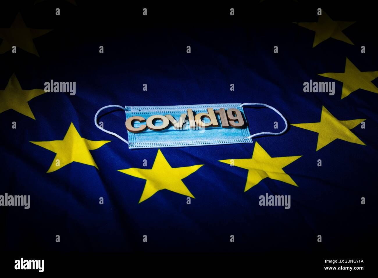 flat face mask on a European flag with wooden letters forming words to create a concept Stock Photo