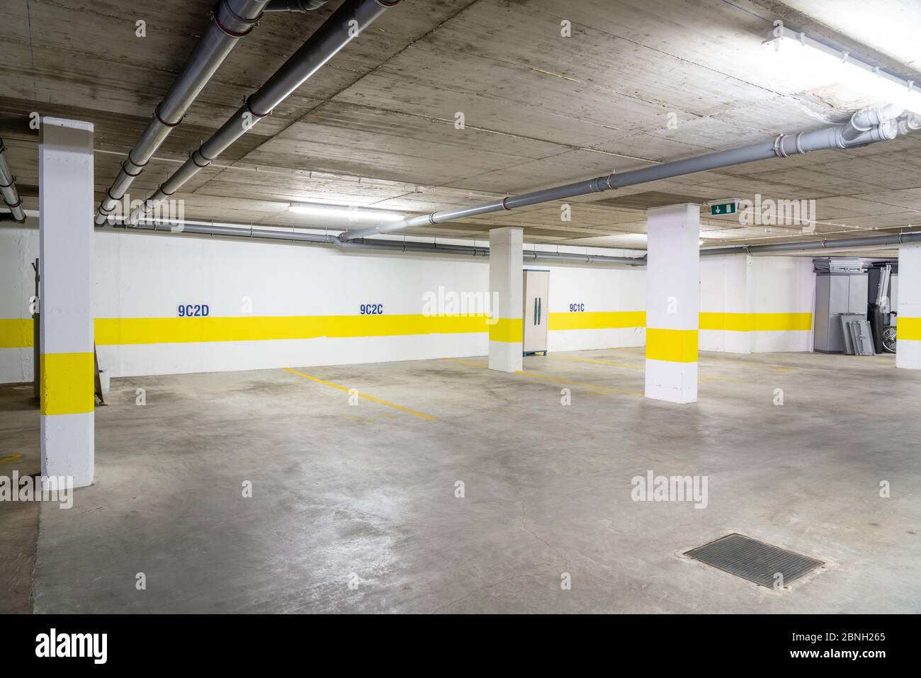 Common garage for parking cars in a multi-storey building with sewer pipes. Stock Photo