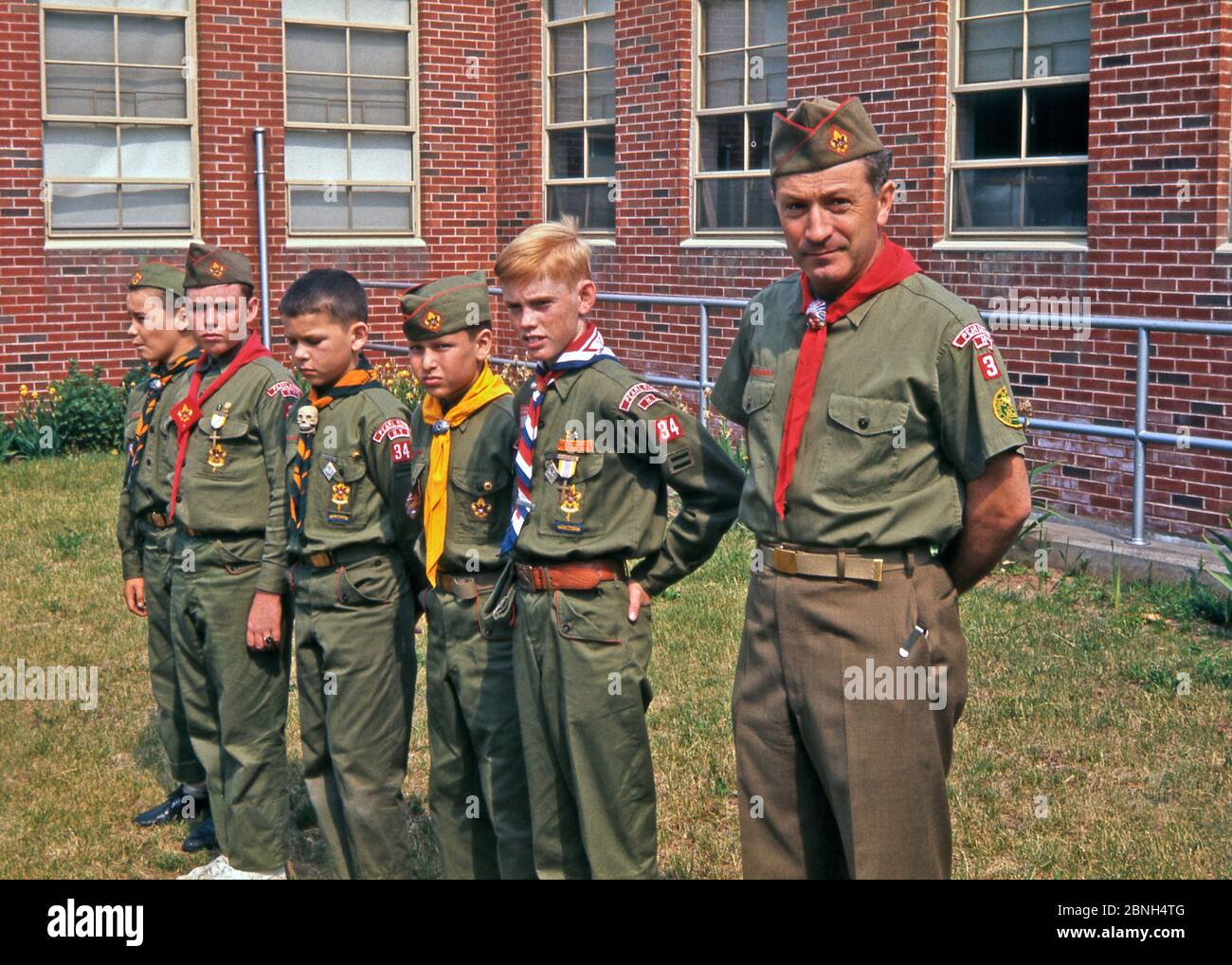 Boy scouts and their leader (Akela) from the Pearl River from number 34 troop (or pack), Pearl River, New York, USA in the mid 60s. The boys display the many badges they have won and wear their distinctive neckerchiefs and slides. The leader has an unusual slide – a Native American in a headdress – whilst the middle boy has a skull slide. Stock Photo