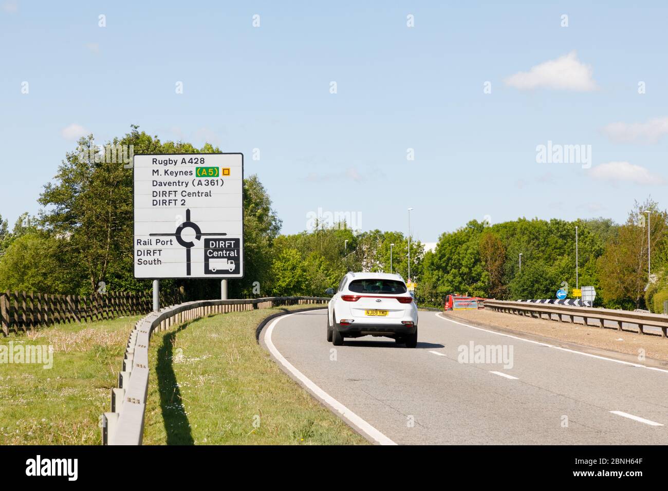 Crick, Northamptonshire, UK - May 2020: Car heads towards road sign with directions to areas of Daventry International Rail Frieght Terminal (DIRFT). Stock Photo