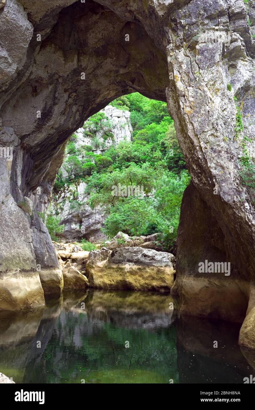 View through one of the natural rock arches, revealing a low water mark, in the river Lamalou, otherwise known as Les Ravin des Arcs, Herault, France Stock Photo