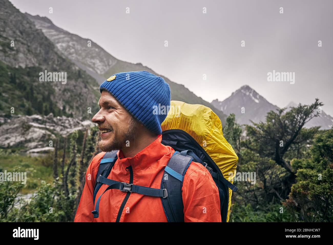 Portrait of happy tourist with big backpack is in the mountain valley of Karakol national park, Kyrgyzstan Stock Photo