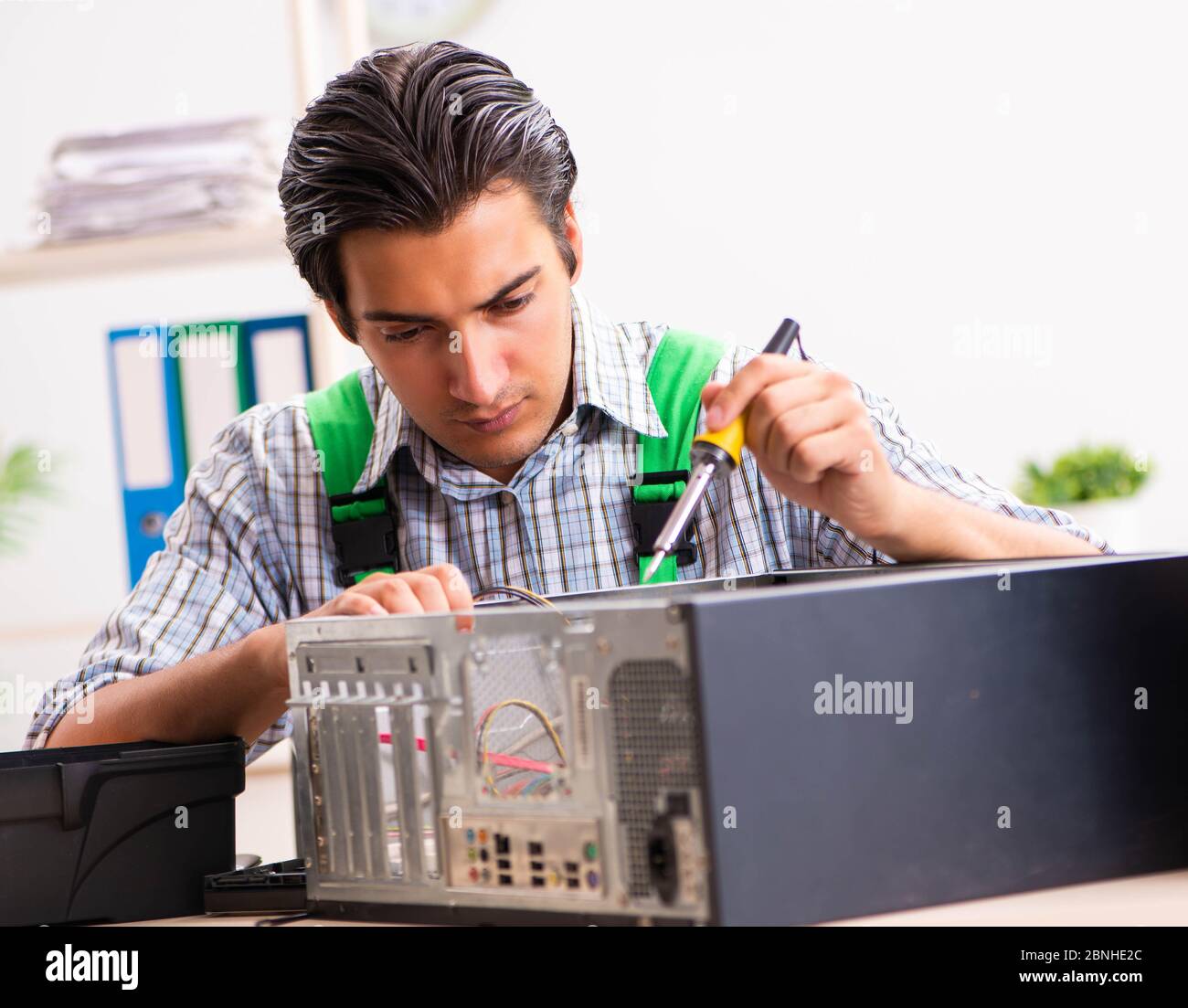 The young engineer repairing broken computer at the office Stock Photo ...