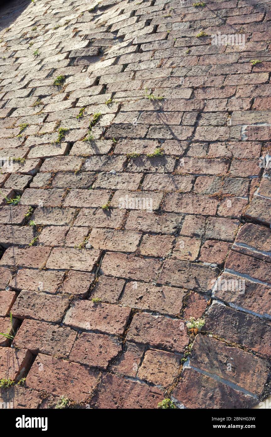 Subsiding or collapsing uneven red brick paving on unstable ground Stock Photo