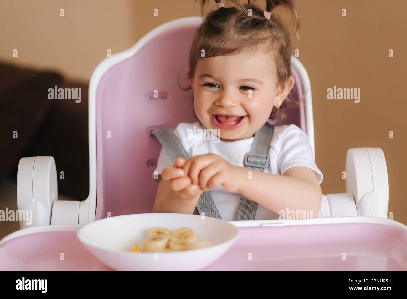 Portrait of cute laughing little girl in hight chair Stock Photo - Alamy