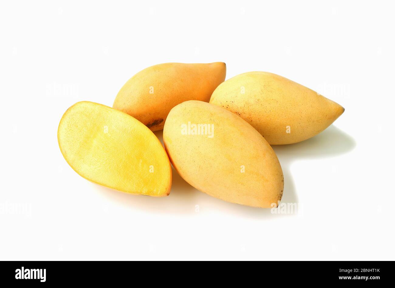 Fresh Ripe Thai Mango Cut in Half with Heap of Whole Fruit Isolated on White Background Stock
